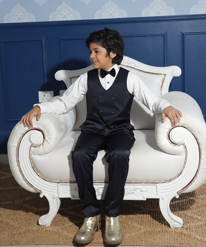 white pleated shirt paired with black waist coat pant & a bow for boys 