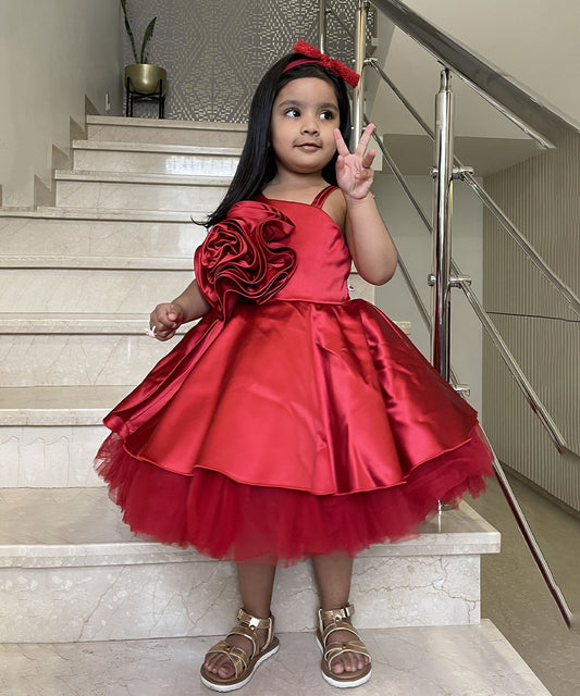 It’s a Red Riding Hood princess frock for kids with a back closure for birthday parties and weddings. It features beautiful big rose detailing that elevates the entire look and comes with a fabric belt to be tied at the back.