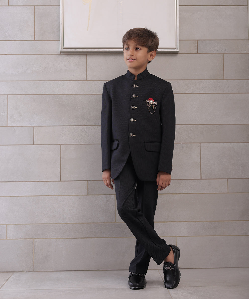  It is a black Jodhpuri suit set which consists of a Jodhpuri Coat along with matching pants. It features stylised buttons, a red coloured pocket square and a nice broach.