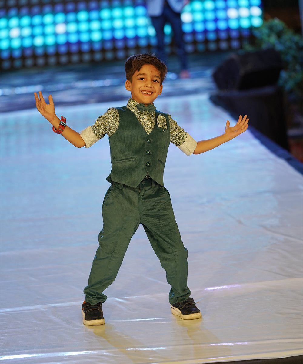 This Green party dress for boys consists of a Waistcoat, a matching pants and a printed shirt. It features a cute broach, a printed pocket square and a matching bow.