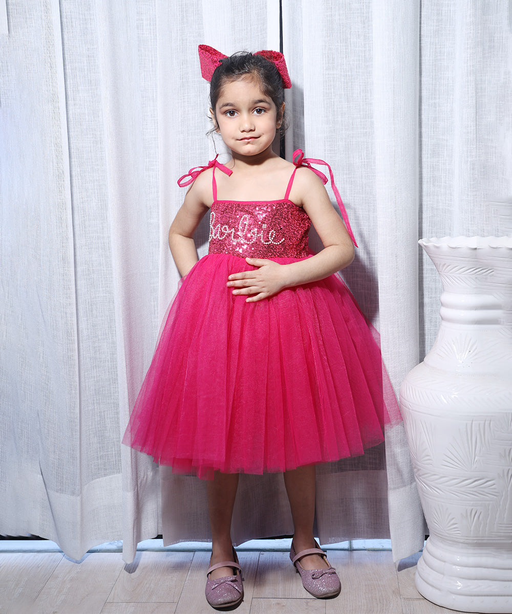  It’s a Pink colored Barbie frock that comes with a back hook closure and is perfect birthday wear for girls. It features a Barbie Inscription on the dress and an attached belt to be tied at the back curated from net fabric.