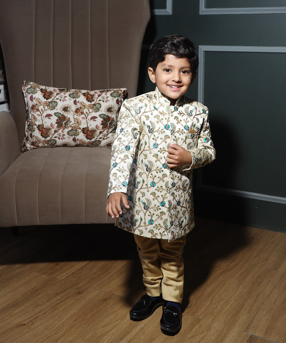 This designer sherwani for boys consists of a self-embroidered Sherwani and a mustard Colored Pyjama. It features a pocket square and stylized buttons on the sherwani that uplift the entire look.