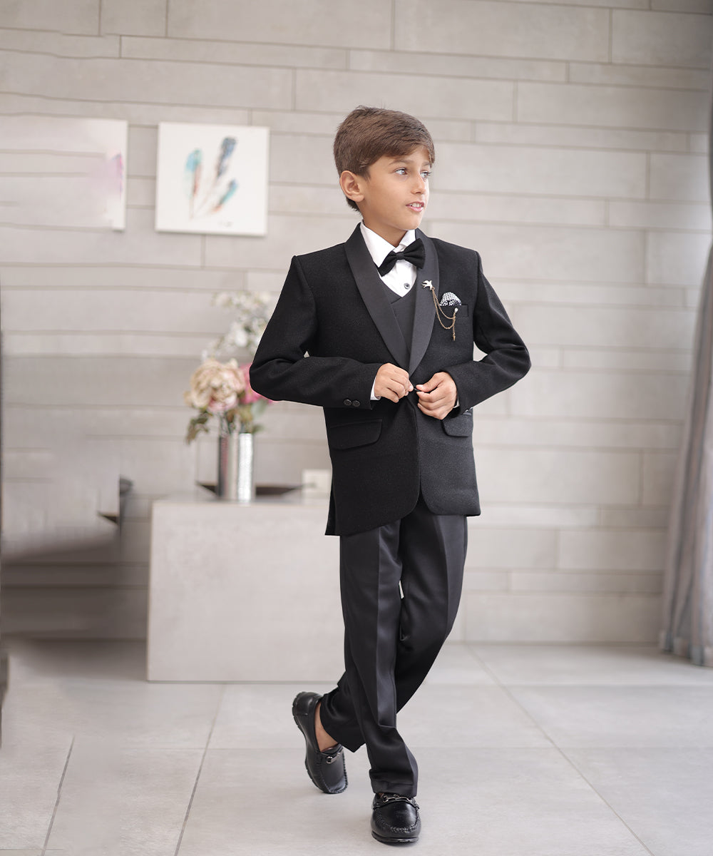 This boys wedding outfit consists of a black Colored shimmer coat, waistcoat, matching pants and a white Colored shirt that comes with pin tucks detailing on it. It features a matching shimmer bow, a broach and a printed pocket square that uplifts the entire look.