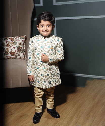 This designer sherwani for boys consists of a self-embroidered Sherwani and a mustard Colored Pyjama. It features a pocket square and stylized buttons on the sherwani that uplift the entire look.